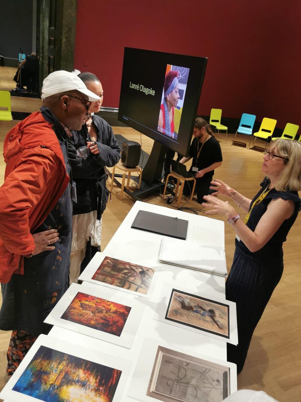 Visitors looking at framed prints laid out on a table