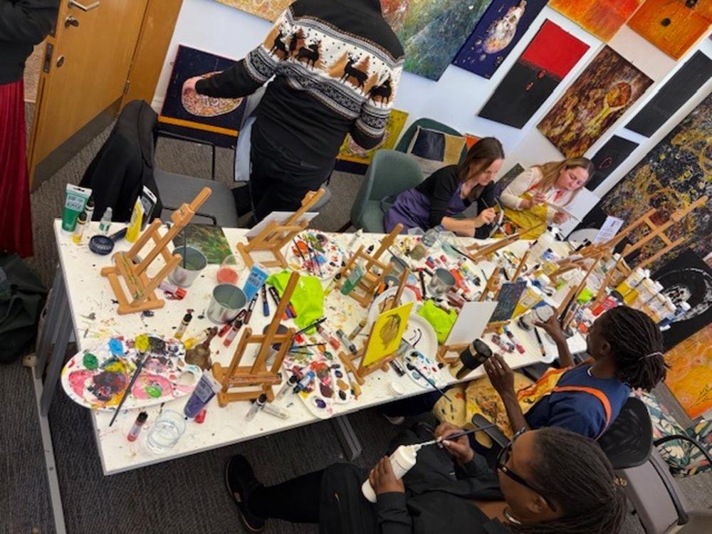 A workshop table covered in paints, brushes and small easels