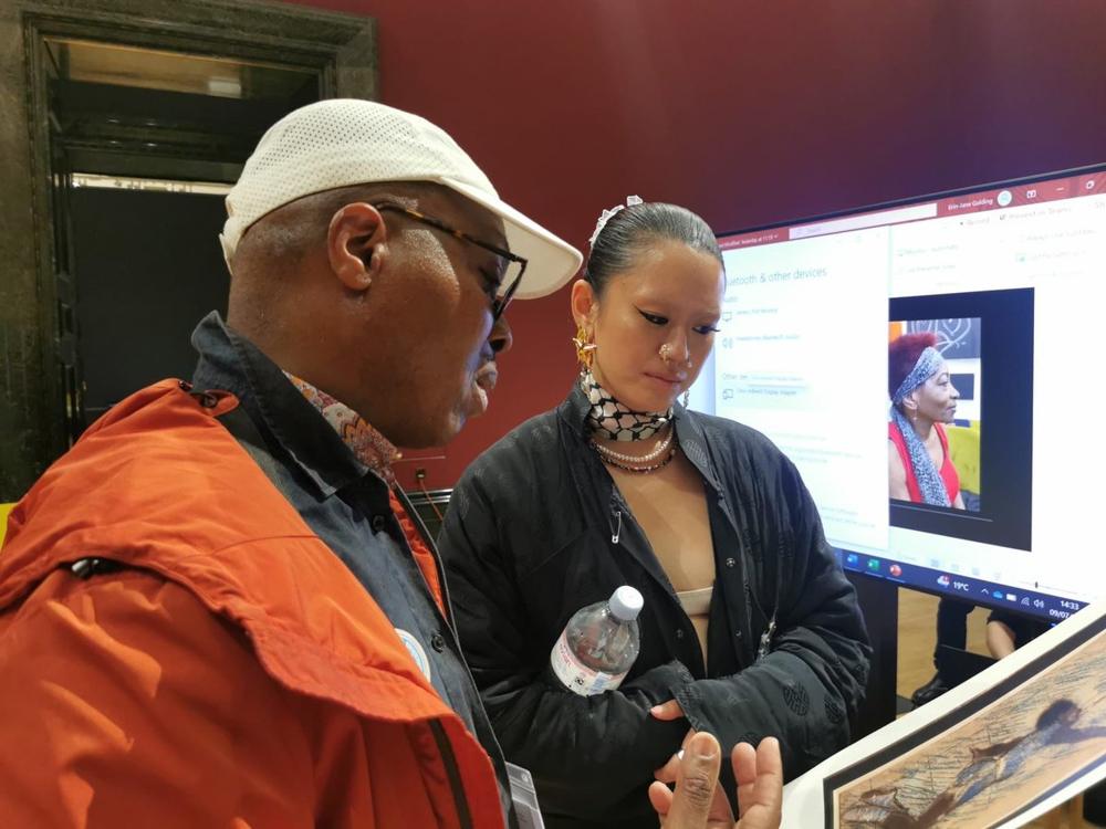 Two people discussing artwork on a screen