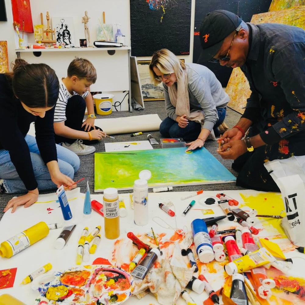 Participants pouring bright paint onto a canvas